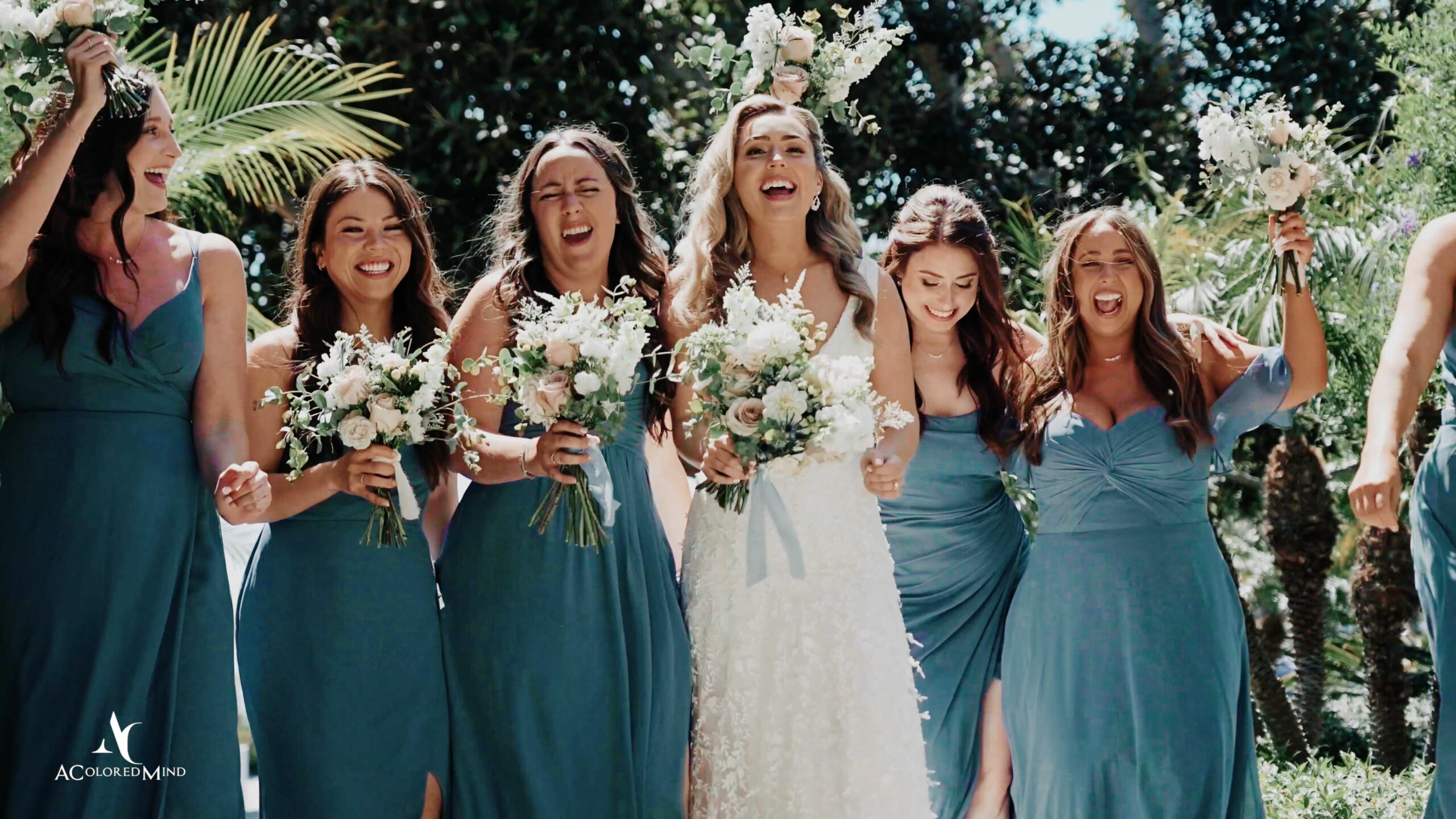 Bride laughing joyfully with bridesmaids in blue dresses, holding bouquets at The Westin Carlsbad Resort & Spa wedding celebration.