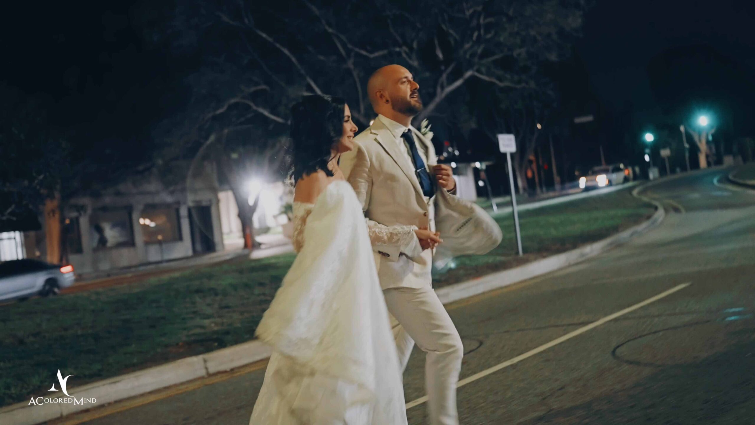 A bride and groom take a romantic night walk down a Beverly Hills street after their wedding reception at Il Cielo, captured in a cinematic Dutch-angle style by a professional wedding photographer.
