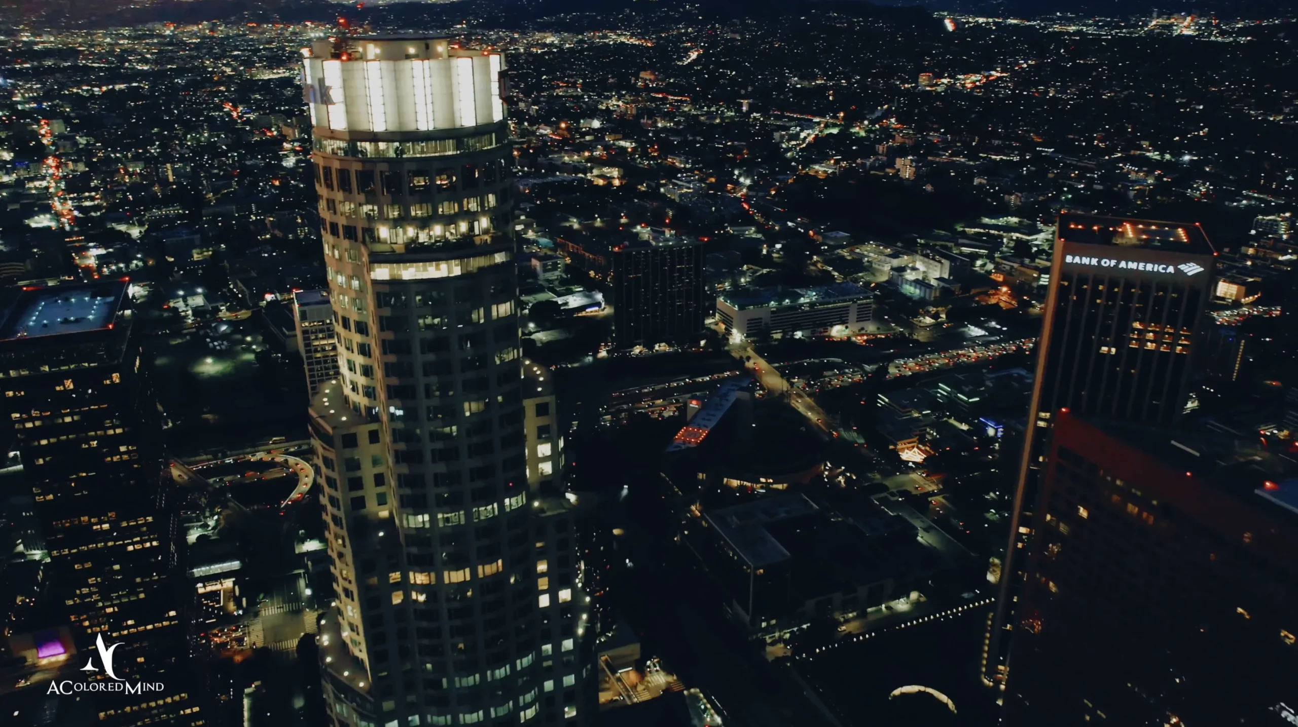 Aerial nighttime view of the illuminated Downtown Los Angeles skyline and skyscrapers, serving as a scenic urban backdrop for an evening rooftop wedding at The Oviatt