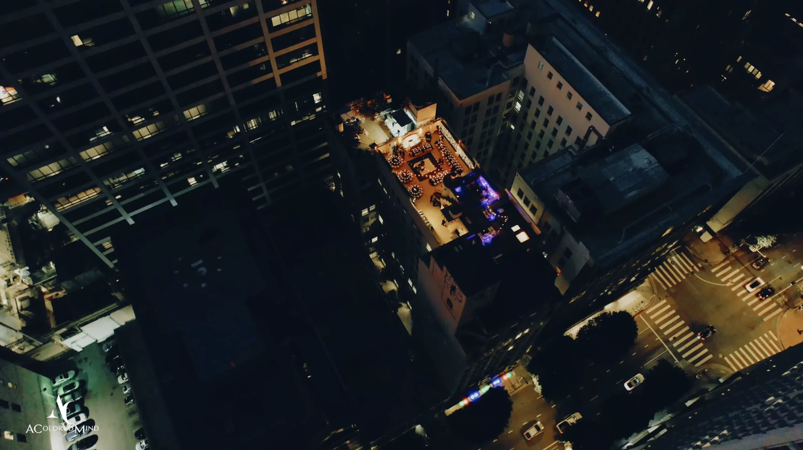 Aerial nighttime view of an illuminated rooftop wedding reception on the two-story terrace at The Oviatt in Downtown Los Angeles, surrounded by city skyscrapers
