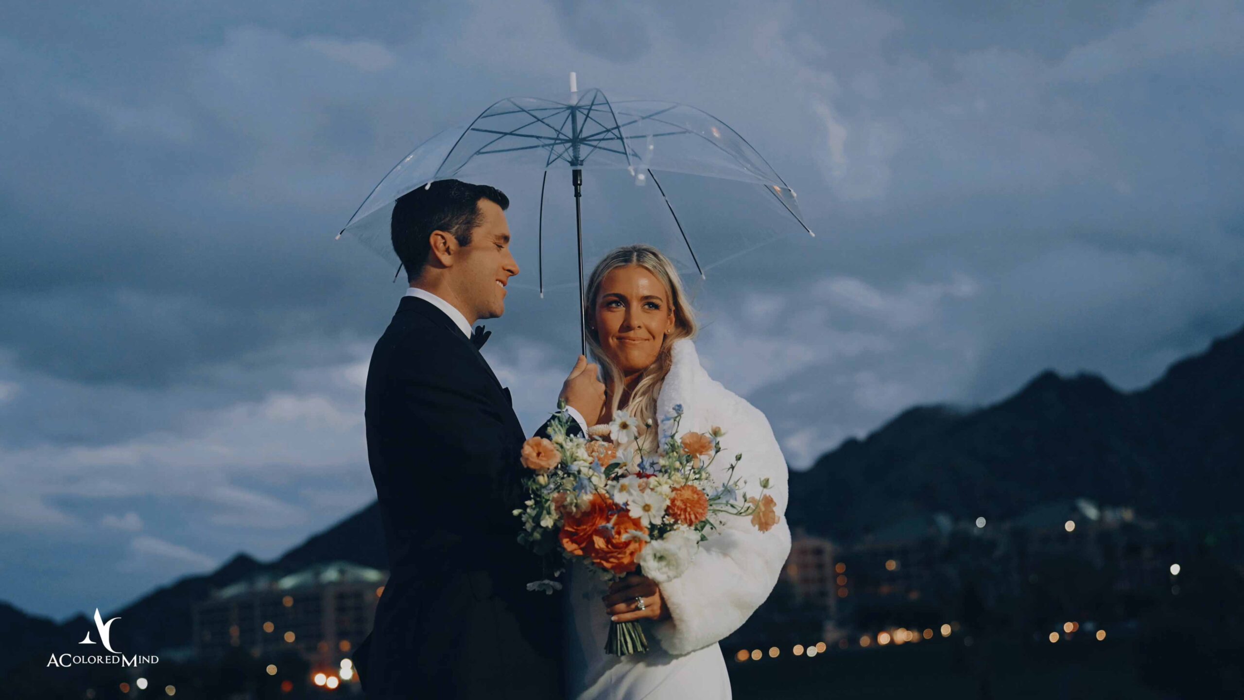 Bride and groom under a clear umbrella during a rainy Indian Wells Golf Resort wedding.