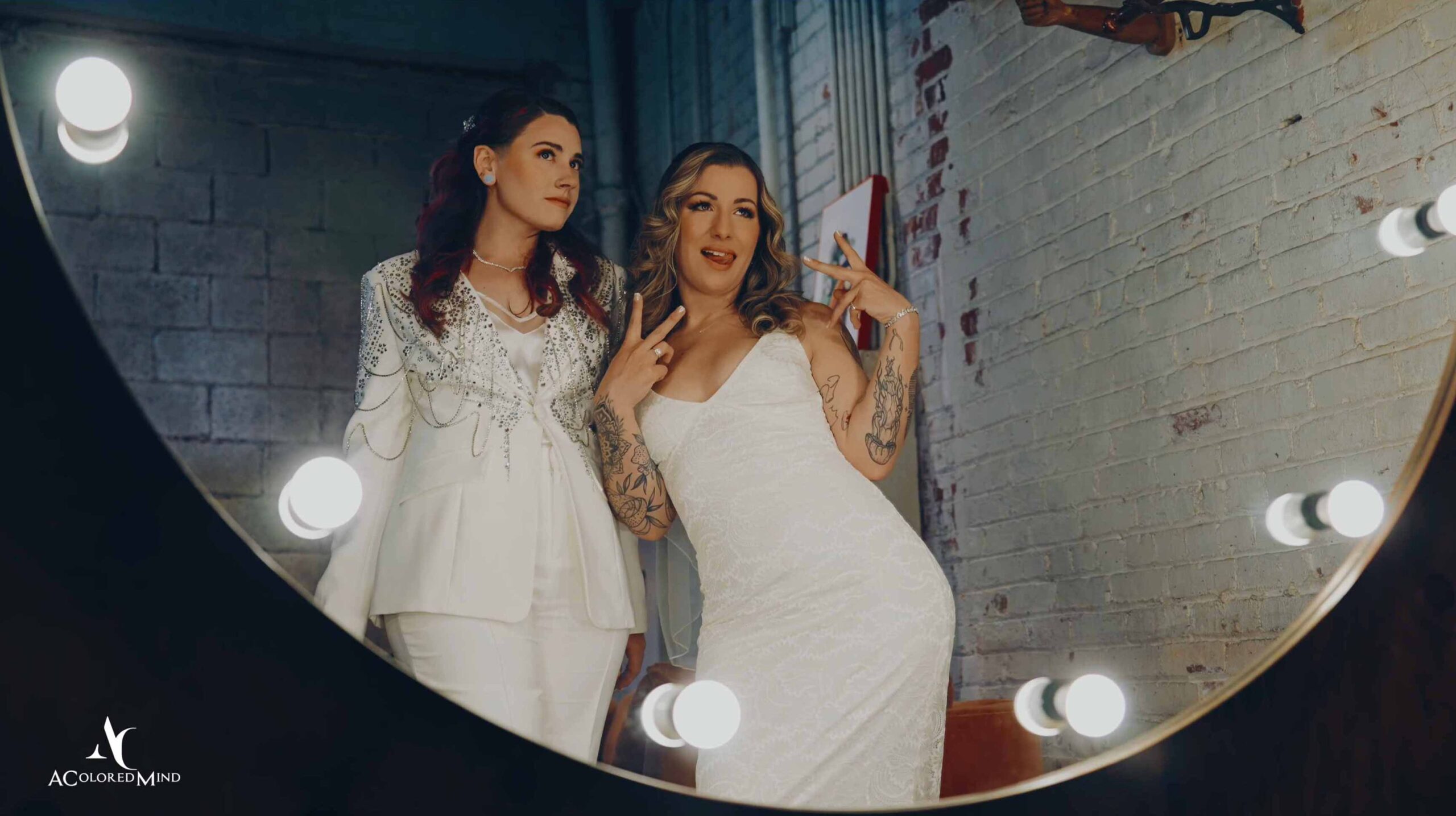 Two brides reflected in a lighted mirror during their Millwick Downtown LA wedding.